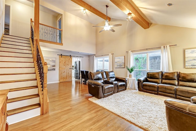 living room featuring hardwood / wood-style floors, high vaulted ceiling, ceiling fan, a barn door, and beamed ceiling