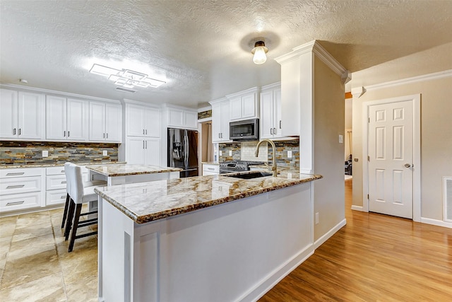 kitchen featuring tasteful backsplash, light stone counters, sink, and appliances with stainless steel finishes