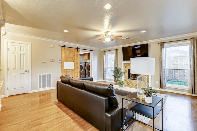 living room featuring a barn door, separate washer and dryer, and crown molding