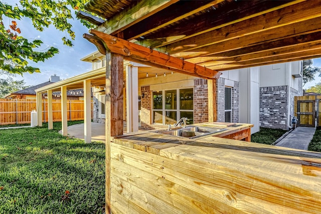 wooden terrace with a lawn, a patio area, and sink