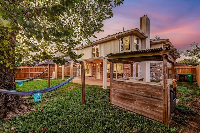 back house at dusk featuring a pergola and a patio