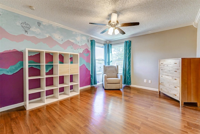 sitting room featuring hardwood / wood-style floors, ceiling fan, crown molding, and a textured ceiling