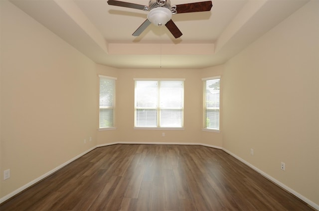 unfurnished room featuring a raised ceiling, ceiling fan, and dark wood-type flooring