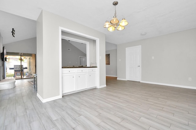 unfurnished living room featuring light wood-type flooring, baseboards, a notable chandelier, and lofted ceiling