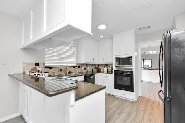 kitchen with a wealth of natural light, sink, kitchen peninsula, white cabinets, and black appliances