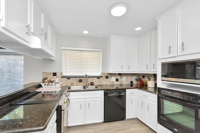 kitchen featuring sink, tasteful backsplash, dark stone countertops, white cabinets, and black appliances