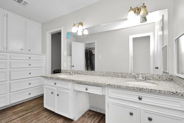 bathroom featuring double vanity, visible vents, a sink, and wood finished floors