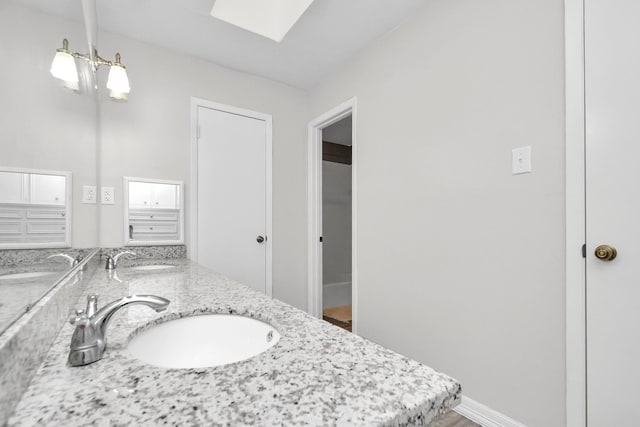 full bathroom featuring a sink, baseboards, and double vanity