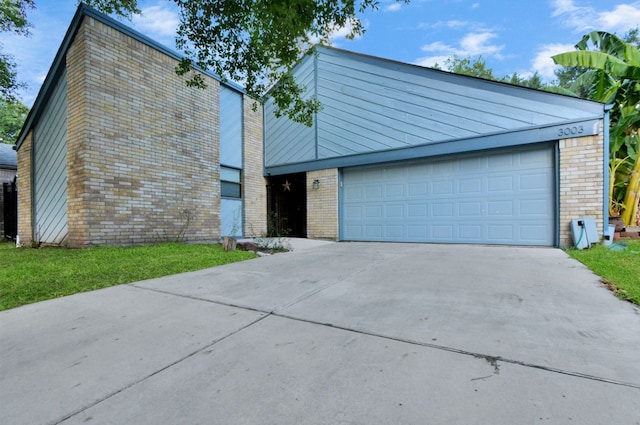 mid-century home with an attached garage, concrete driveway, and brick siding