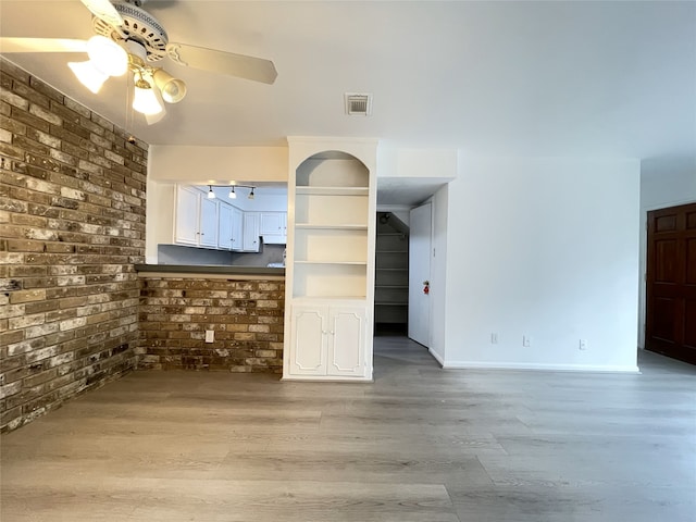 interior space featuring brick wall, ceiling fan, and light hardwood / wood-style floors