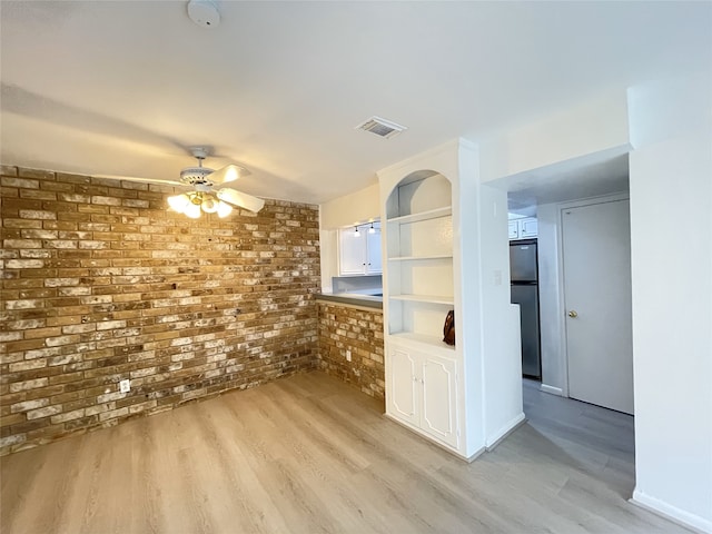 interior space featuring brick wall, light wood-type flooring, and ceiling fan