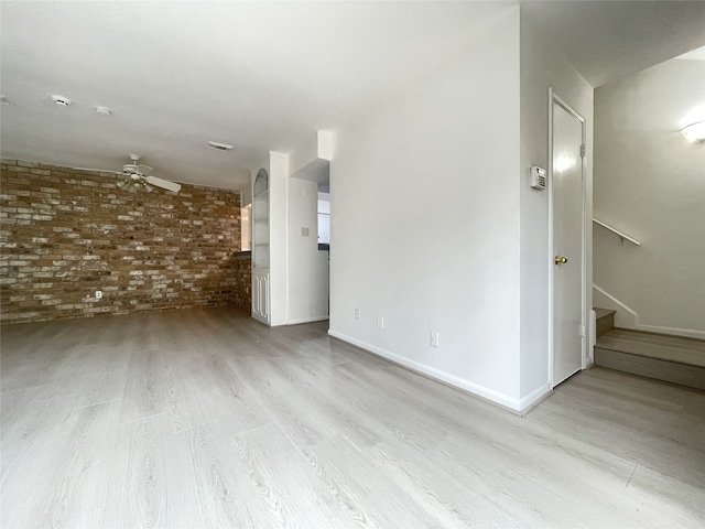 spare room with brick wall, ceiling fan, and light hardwood / wood-style flooring