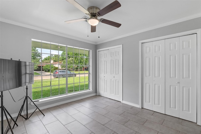 unfurnished bedroom featuring ceiling fan, light tile patterned flooring, two closets, and ornamental molding