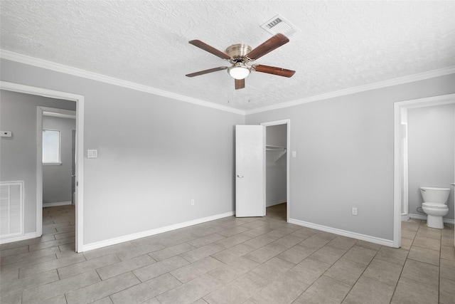 unfurnished bedroom featuring ensuite bath, a spacious closet, ceiling fan, and ornamental molding