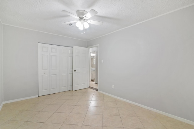 unfurnished bedroom featuring a textured ceiling, a closet, ceiling fan, and light tile patterned flooring