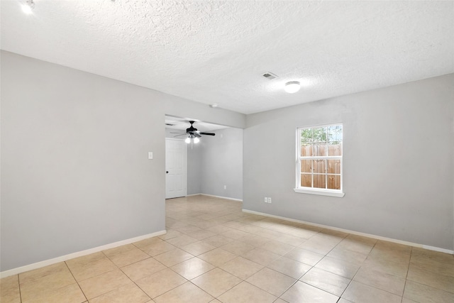 empty room with ceiling fan, light tile patterned floors, and a textured ceiling