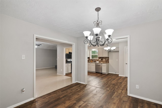 unfurnished dining area featuring a chandelier, a textured ceiling, and dark hardwood / wood-style floors