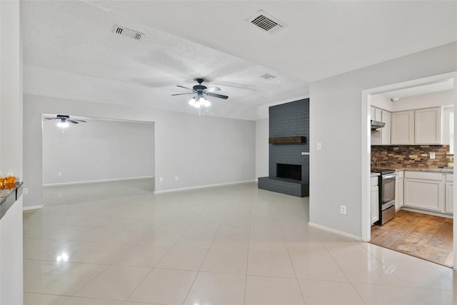 unfurnished living room featuring ceiling fan, a fireplace, light tile patterned floors, and a textured ceiling