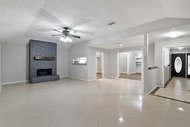 unfurnished living room with a brick fireplace, a textured ceiling, vaulted ceiling, ceiling fan, and light tile patterned flooring