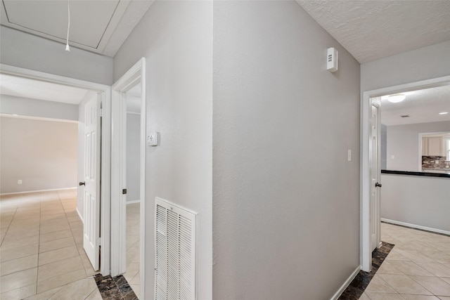 hall with light tile patterned flooring and a textured ceiling