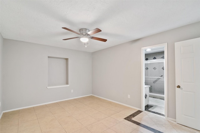 unfurnished room with ceiling fan, light tile patterned floors, and a textured ceiling