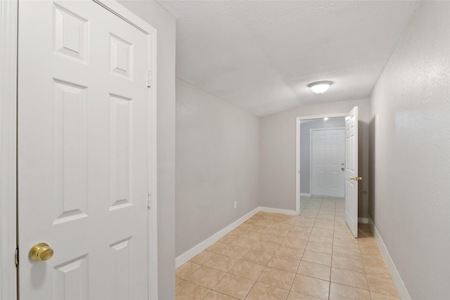 hallway featuring light tile patterned floors, a textured ceiling, and lofted ceiling