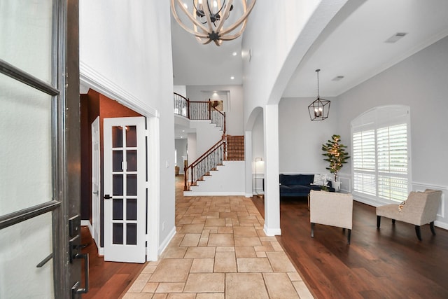 foyer with crown molding, a chandelier, and a high ceiling