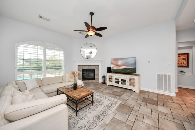 living room featuring ceiling fan and a tiled fireplace