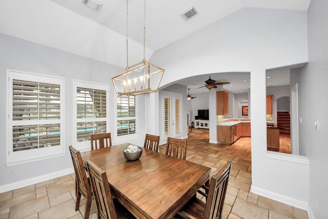 dining room featuring ceiling fan with notable chandelier and lofted ceiling