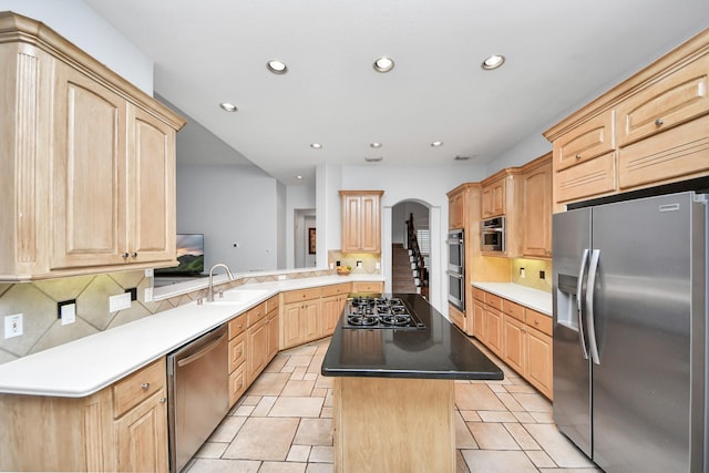 kitchen with kitchen peninsula, appliances with stainless steel finishes, and light brown cabinetry