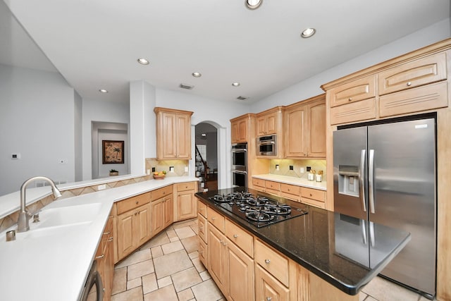 kitchen featuring sink, decorative backsplash, light brown cabinetry, a kitchen island, and appliances with stainless steel finishes