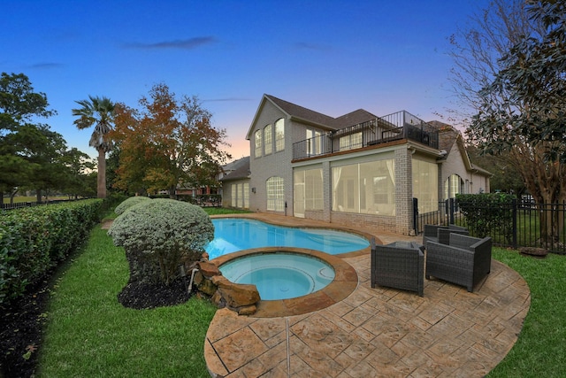 pool at dusk with an in ground hot tub, a yard, and a patio area