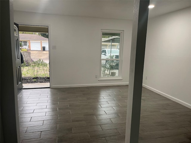 empty room with dark hardwood / wood-style flooring and plenty of natural light