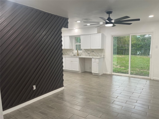 kitchen featuring built in desk, white cabinetry, sink, decorative backsplash, and ceiling fan