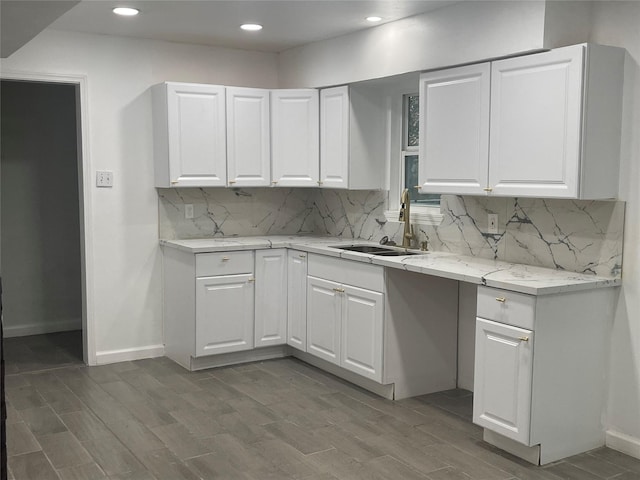 kitchen featuring dark wood-type flooring, sink, white cabinetry, light stone countertops, and decorative backsplash