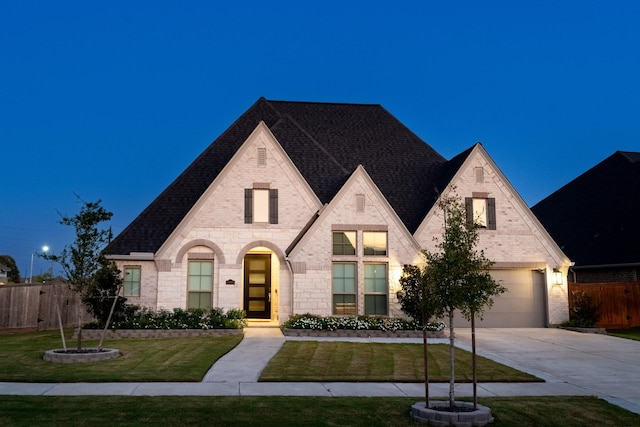 view of front facade featuring brick siding, a front yard, fence, a garage, and driveway