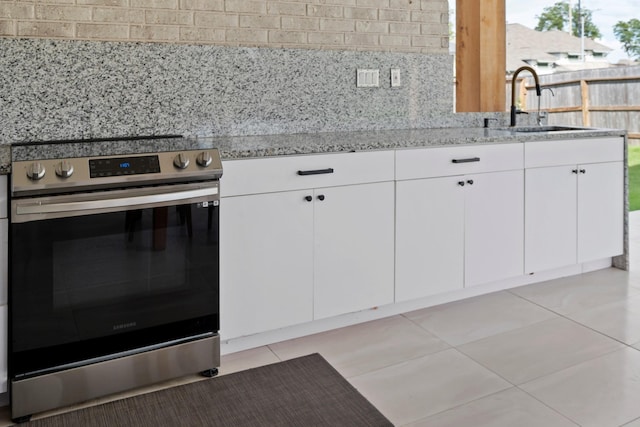 kitchen with stainless steel range with electric stovetop, white cabinets, a sink, and light stone countertops