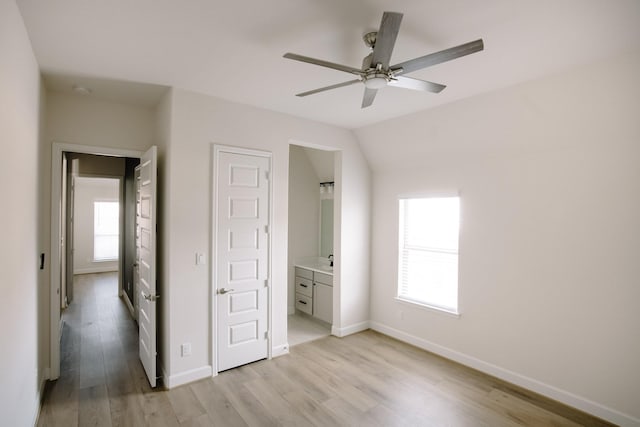 unfurnished bedroom featuring light wood finished floors, multiple windows, baseboards, and ensuite bathroom