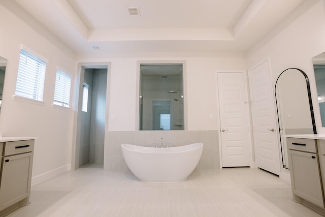 bathroom with vanity, tile walls, a soaking tub, a tray ceiling, and walk in shower