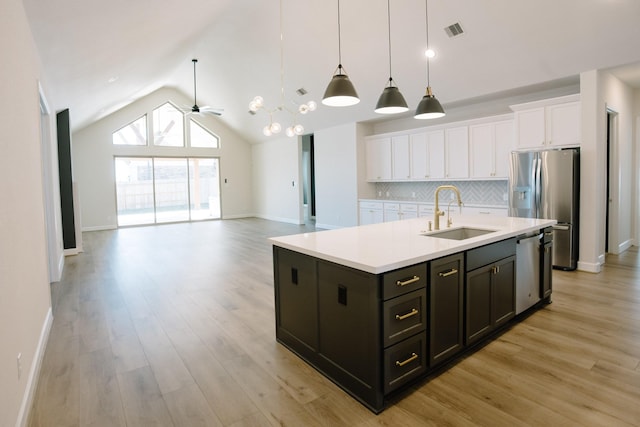 kitchen featuring stainless steel appliances, a sink, white cabinetry, open floor plan, and light countertops