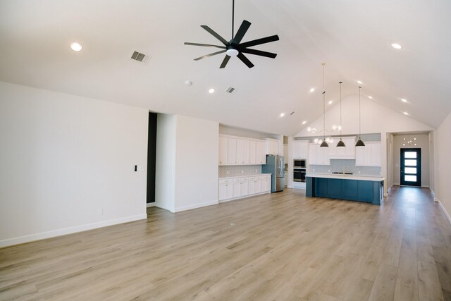 kitchen with open floor plan, light countertops, a kitchen island with sink, and stainless steel appliances