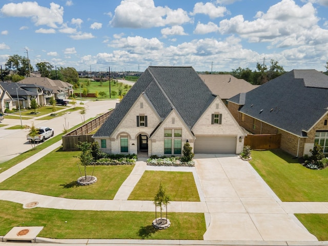 french provincial home featuring a garage, concrete driveway, a residential view, fence, and a front lawn