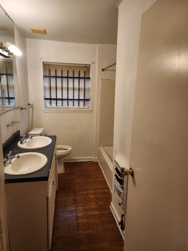 full bathroom featuring wood-type flooring, vanity, toilet, shower / bathtub combination, and heating unit