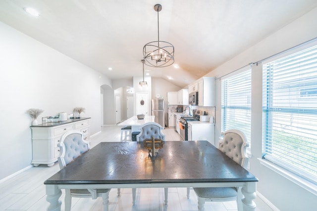 dining area with a chandelier and vaulted ceiling