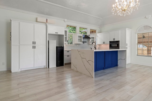 kitchen with ventilation hood, oven, a center island with sink, hanging light fixtures, and white cabinetry