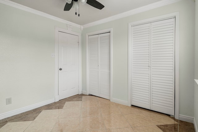 unfurnished bedroom featuring ceiling fan, light tile patterned floors, and multiple closets