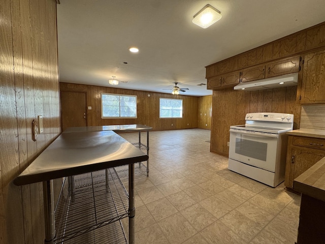 kitchen with ceiling fan, wood walls, and electric stove