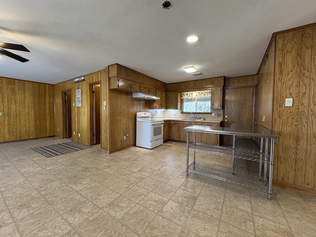 kitchen featuring electric stove, wood walls, sink, and ceiling fan