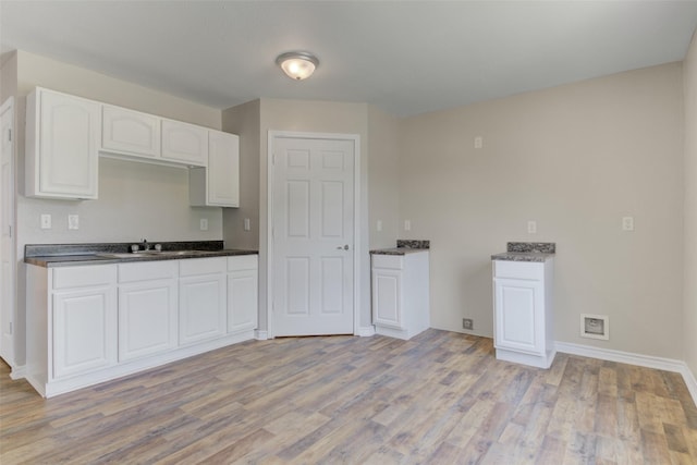 kitchen with white cabinets, light wood-type flooring, and sink