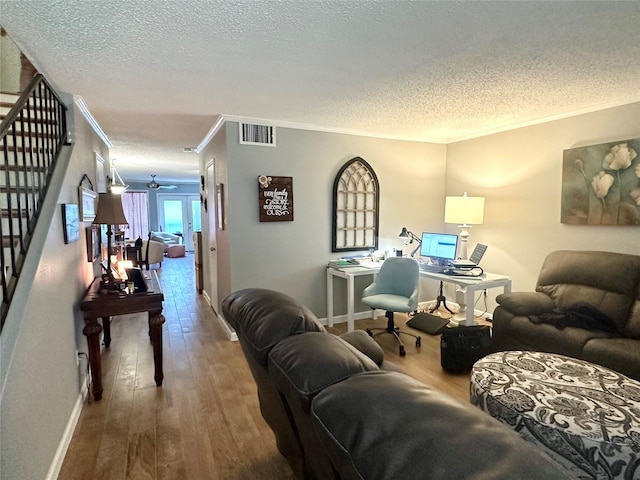 living room with hardwood / wood-style floors, a textured ceiling, ceiling fan, and crown molding